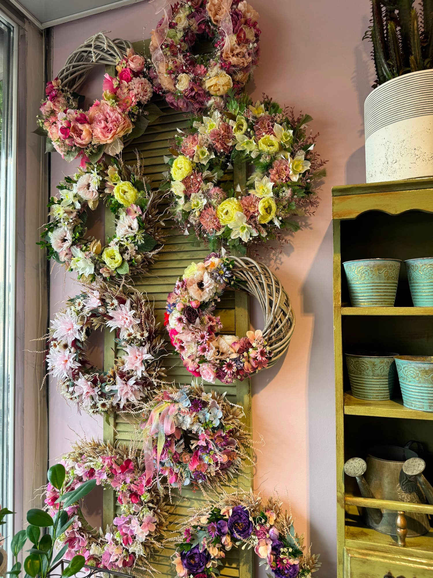 A wall of dried wreaths on an old shutter in the shop