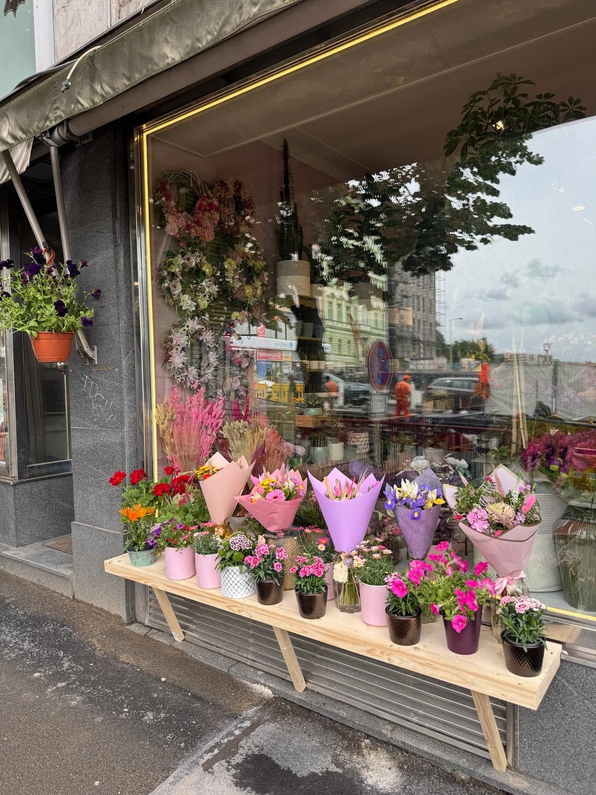 The Květiny nad museem shopfront from the street with a bench of bouquets
