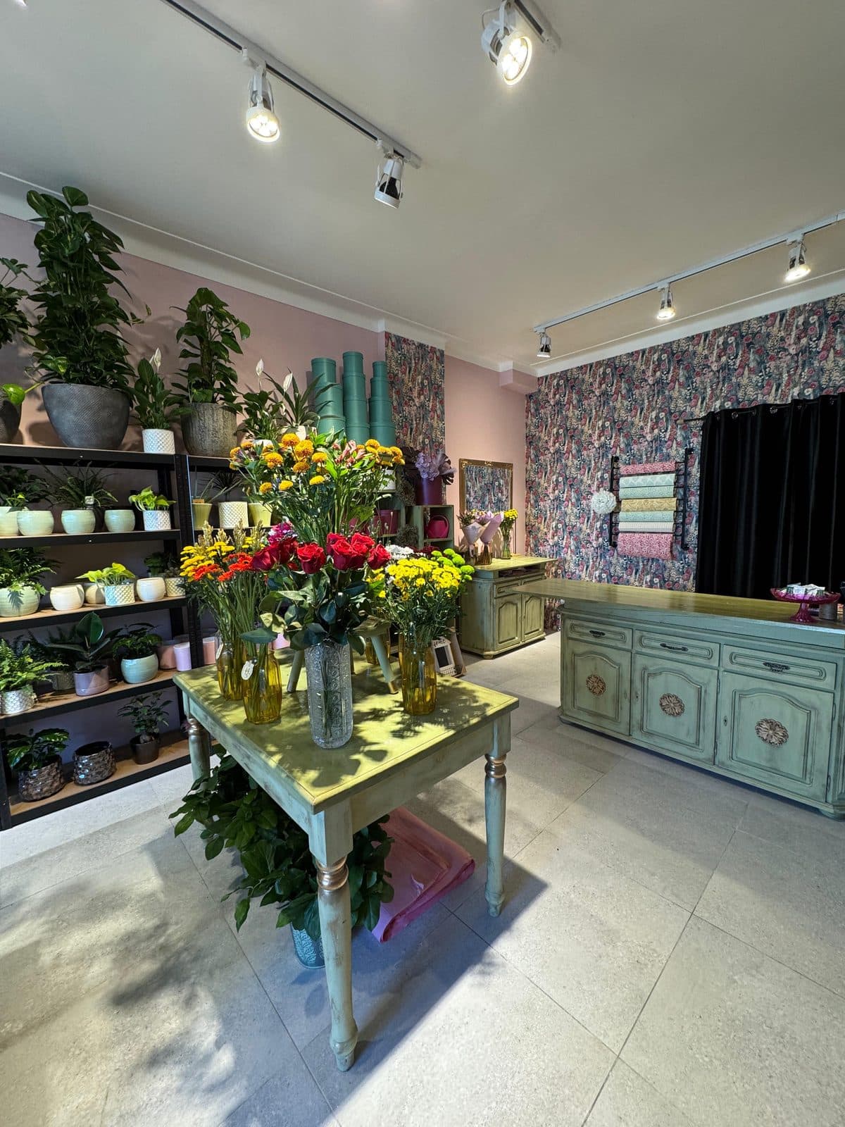 A workbench with bouquets in front of a floral tapestry